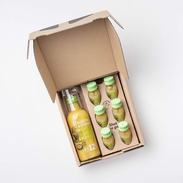 The Ginger Shot Pineapple box opened so you can see the contents: 1 360 ml bottle of Ginger Shot Pineapple, 6x 30 ml Ginger Shot Pineapple + 1 shot glass.