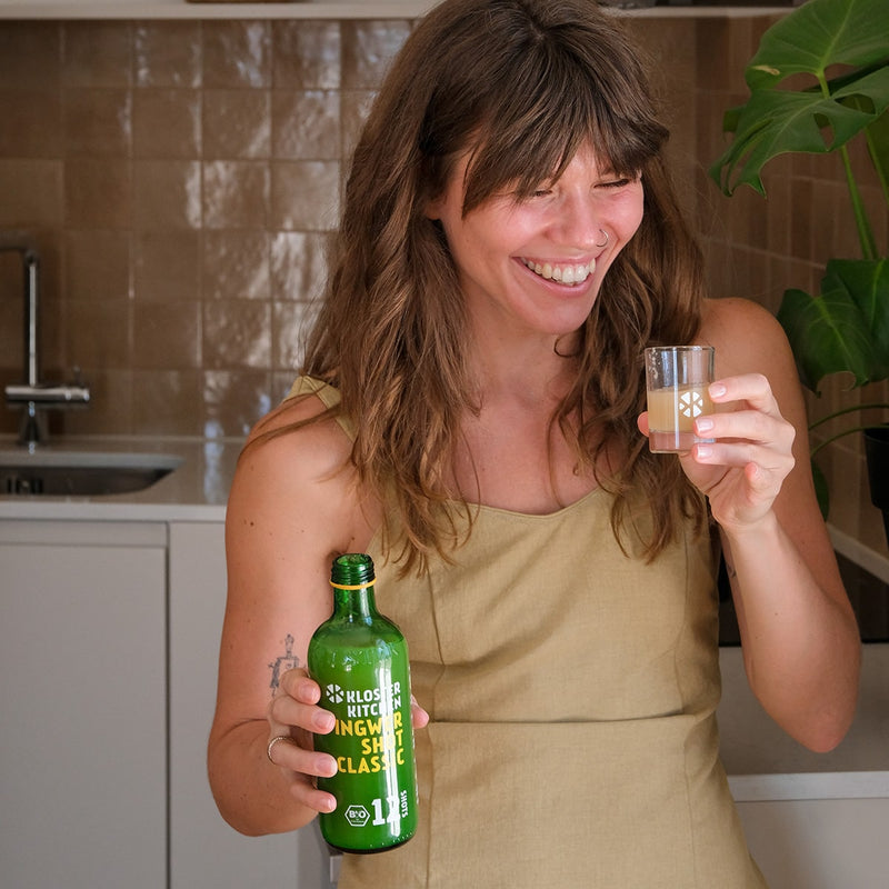 Woman holding a ginger Shot Classic 12SHOTS single bottle